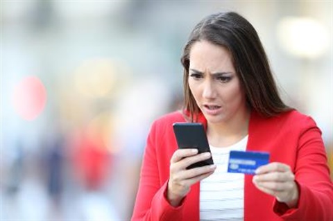 lady looking shocked into her phone holding credit card